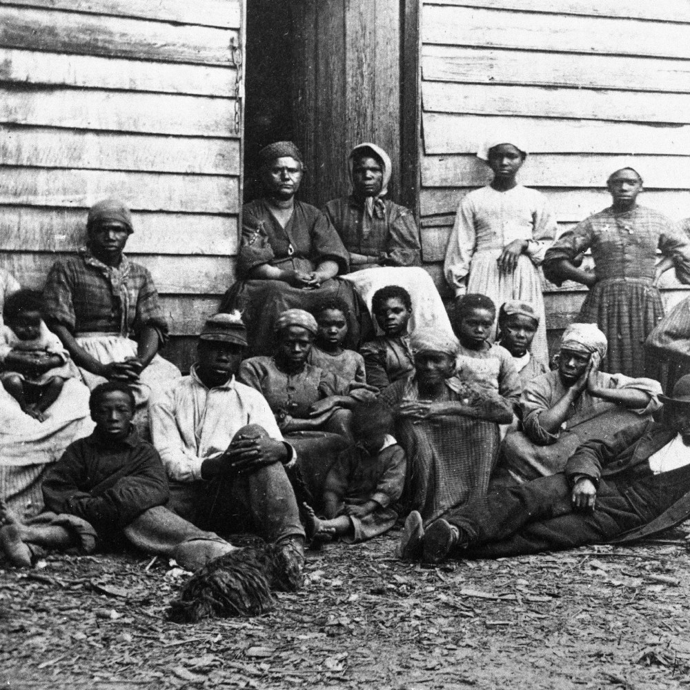 Civil War ‘contrabands,’ fugitive slaves who were emancipated upon reaching the North, sitting outside a house in the mid 1860s. Freedman’s Village was a shelter for runaway and liberated slaves.